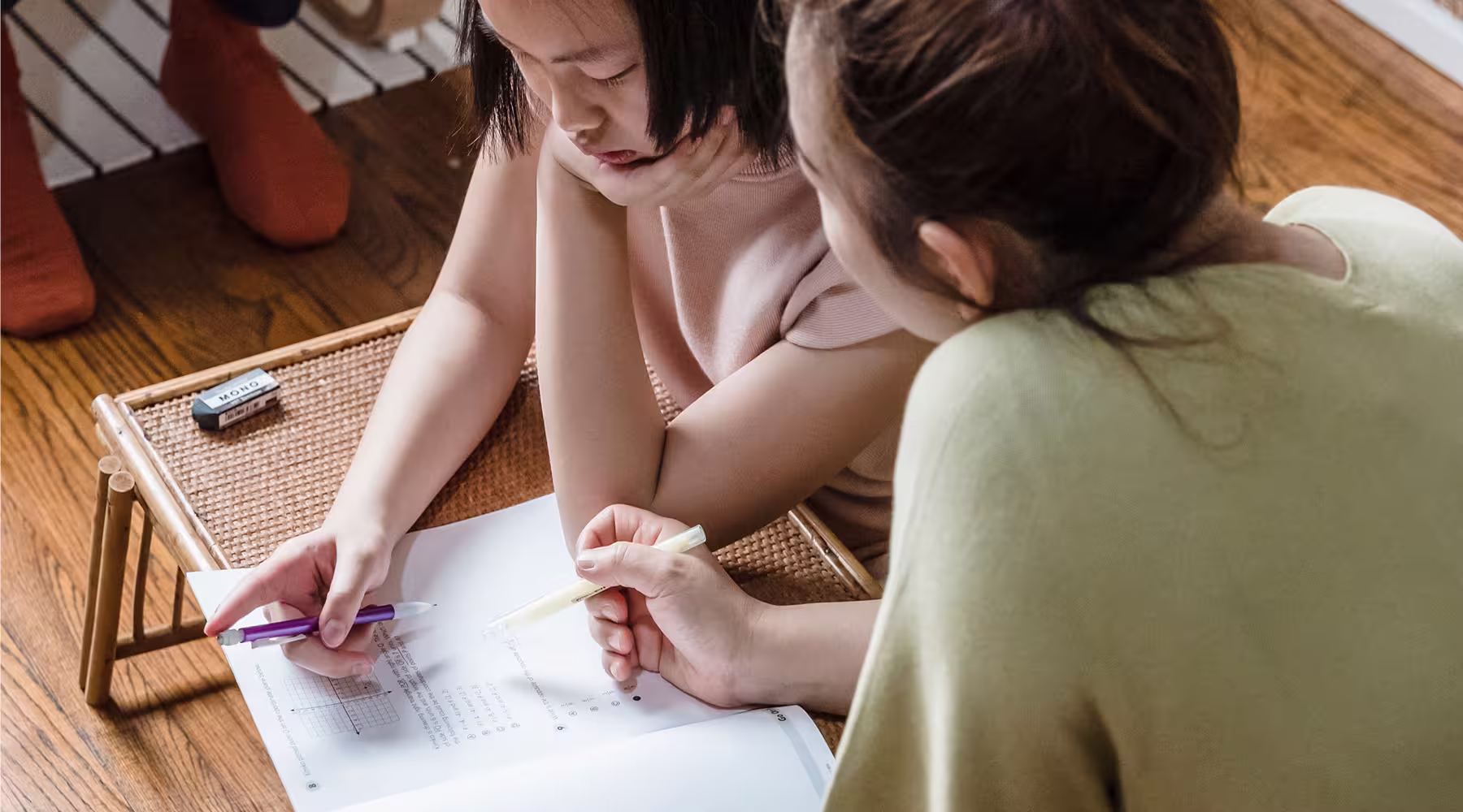 Adult supporting a child as they complete a reading and writing worksheet.