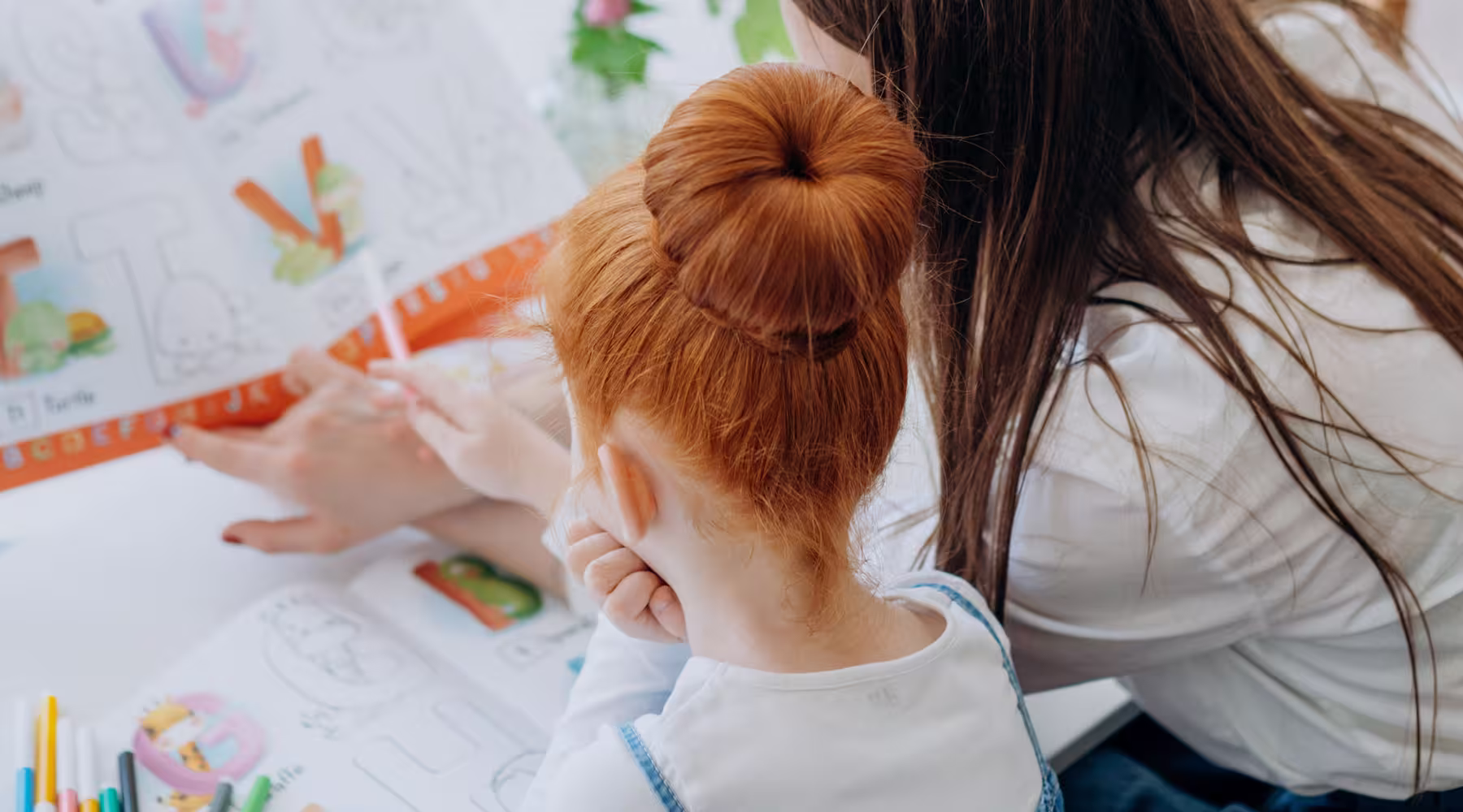 Adult pointing to a large worksheet while a child follows along.