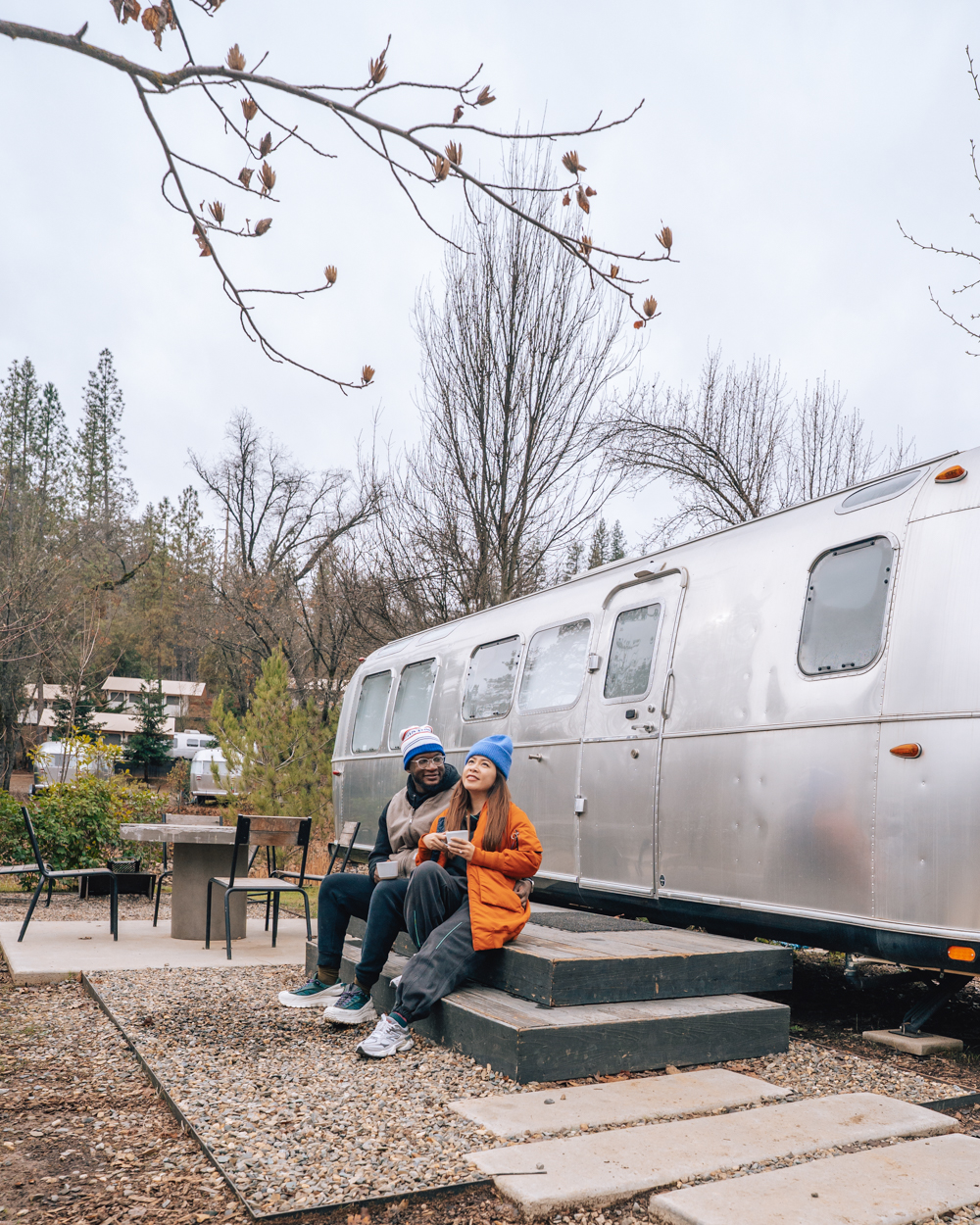 Cindy and her partner outside of a camper in the woods. 