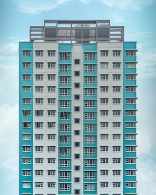 A front view image of a blue and white striped residential apartment building
