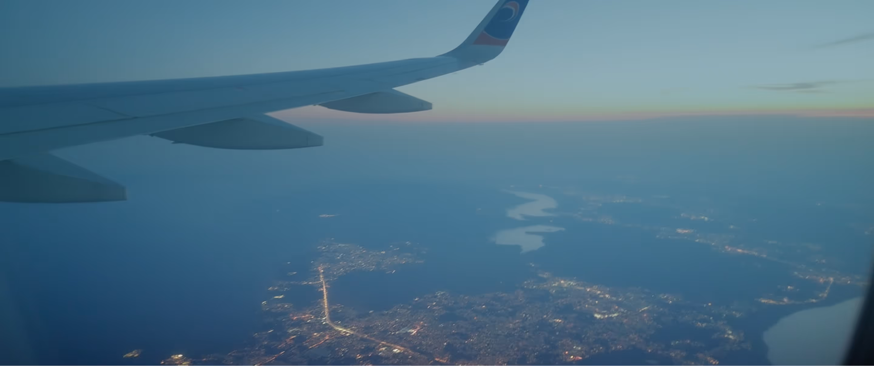 Airplane window view over a city at dusk