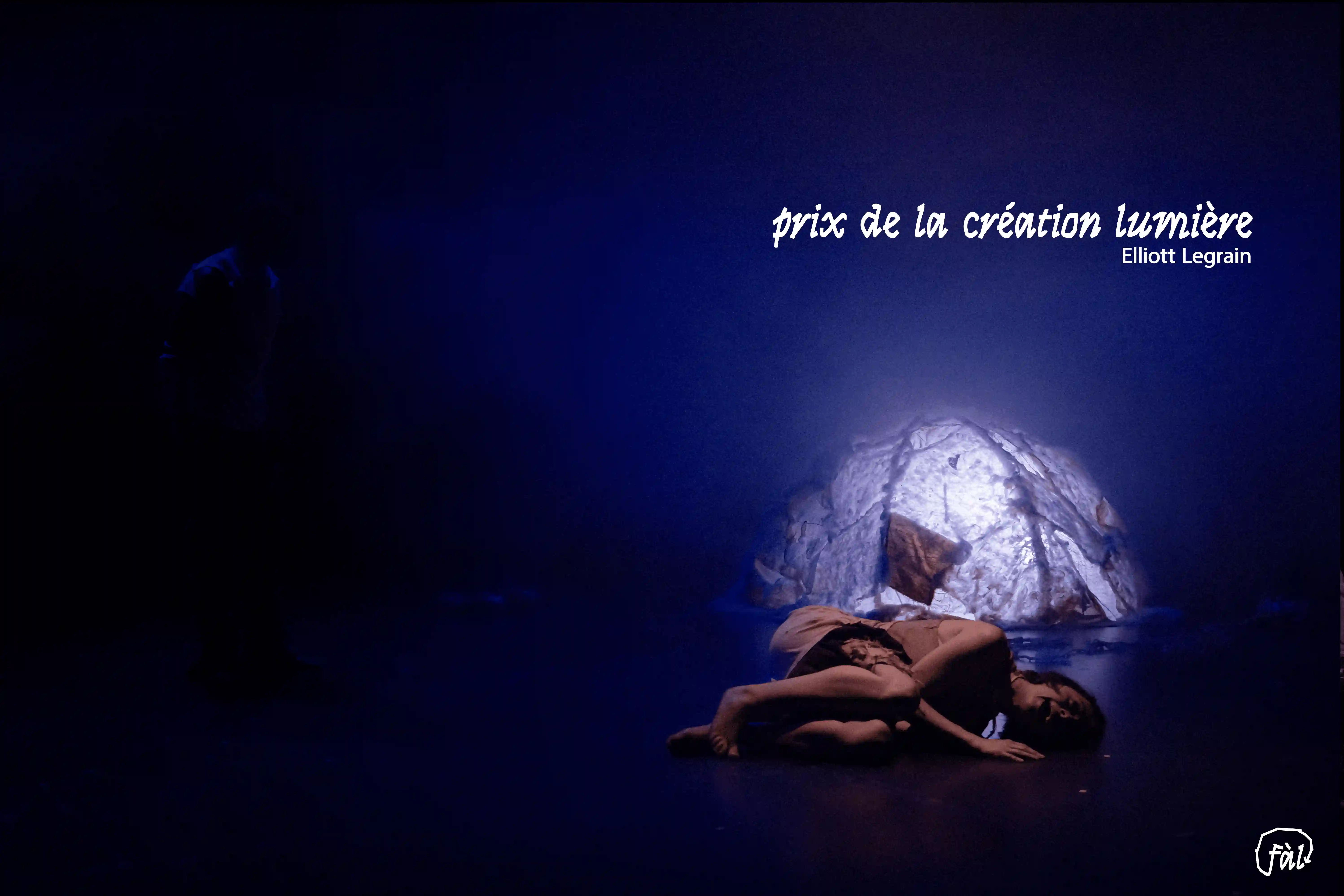 Scène baignée d’une lumière bleutée, performeuse allongée au sol devant un décor lumineux — texte “prix de la création lumière – Elliott Legrain”.