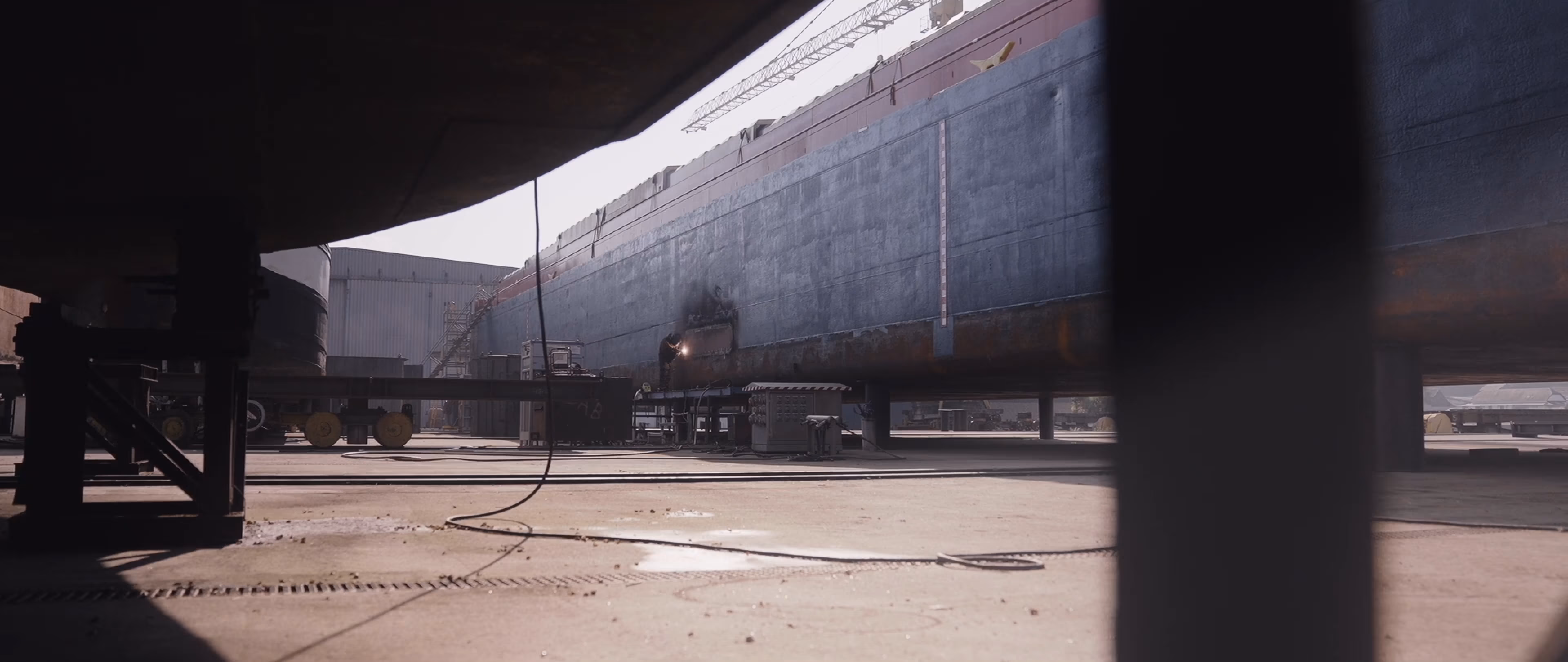A cinematic shot of shipyard construction worker welding a big ship