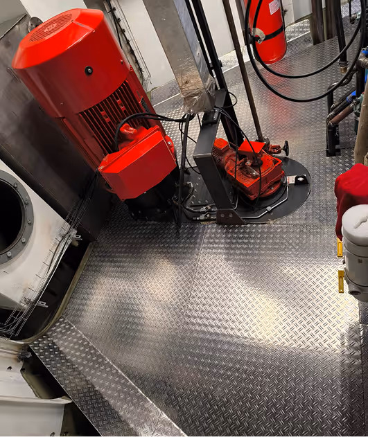 Rode industriële motor in machinekamer met metalen vloer.