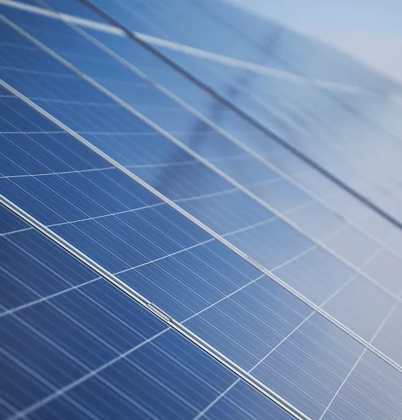 Close-up of blue solar panels under clear sky, showing grid lines and reflective surface.