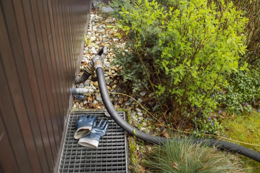 Ölheizung erneuern: Heizöllieferung: Schlauch führt durch den Garten und Heizöl wird in das Haus geliefert