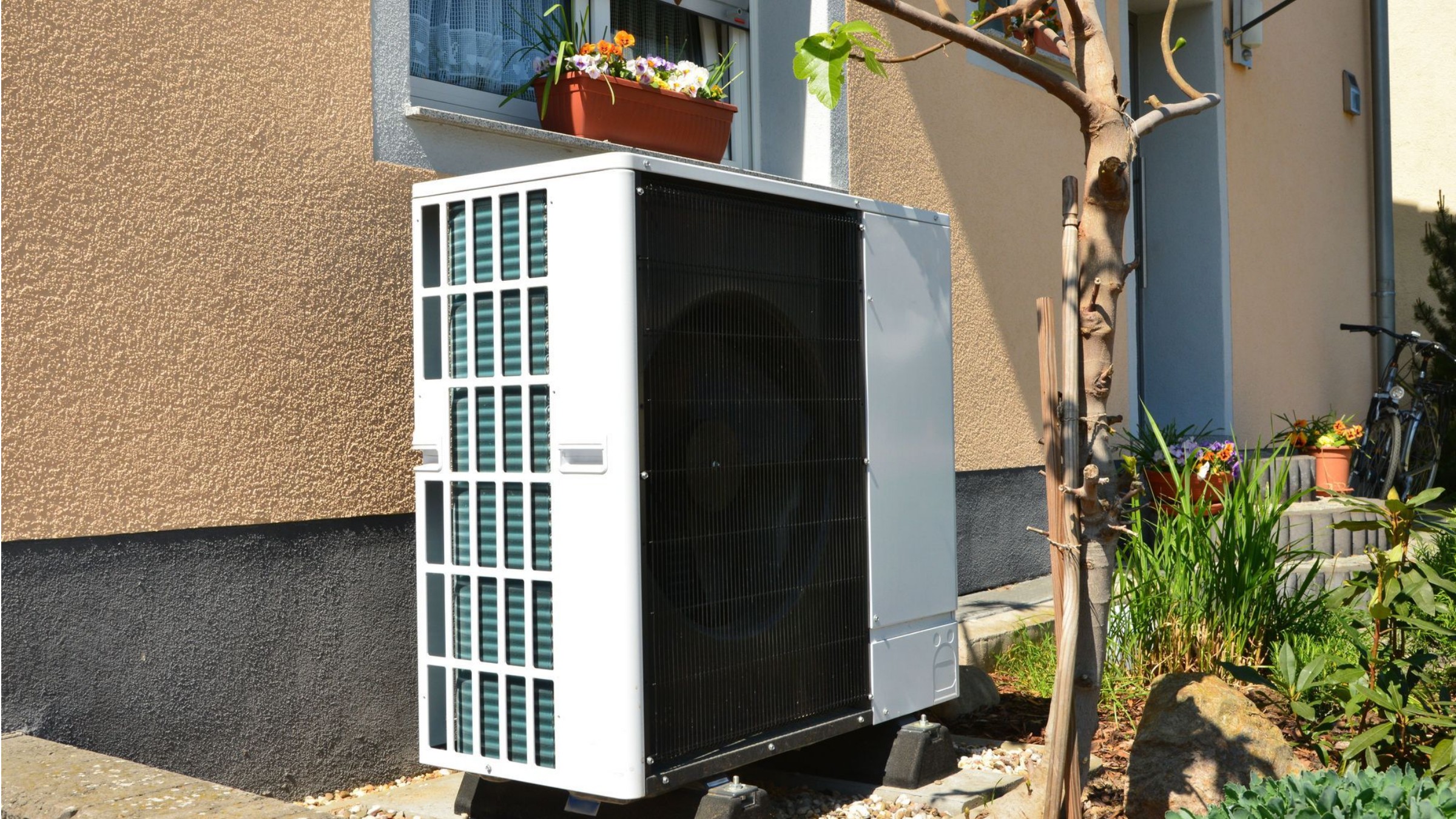 Luftwärmepumpe vor Altbau mit sanierter Putzfassade.