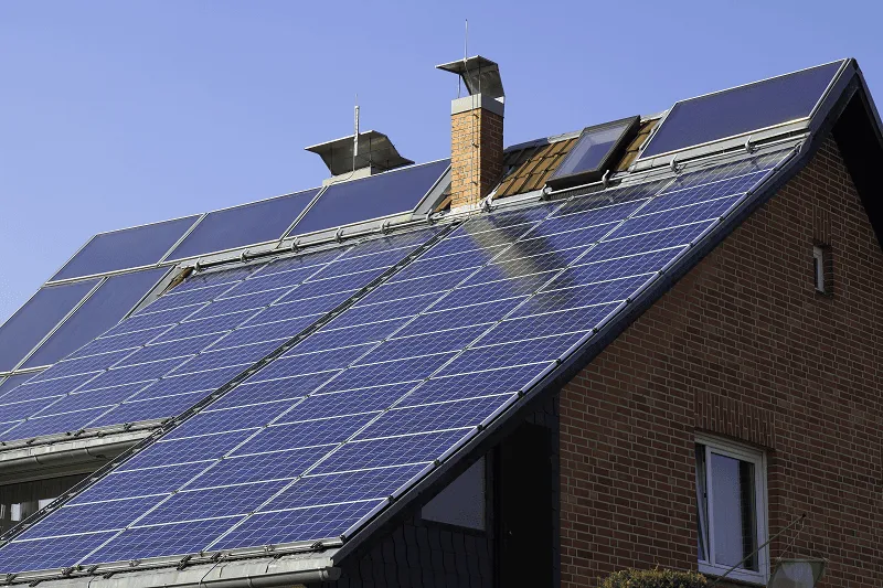 Photovoltaikförderung: Einfamilienhaus mit Photovoltaik und Solarthermiekollektoren auf dem Dach.