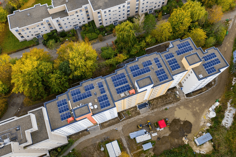 PV Förderung: Luftaufnahme von Mehrfamilienhäusern mit Photovoltaik auf den Dächern.
