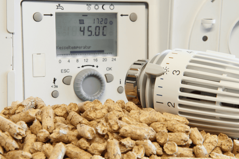 Pellets und Thermostat vor einer Pelletheizung-Kontrolleinheit
