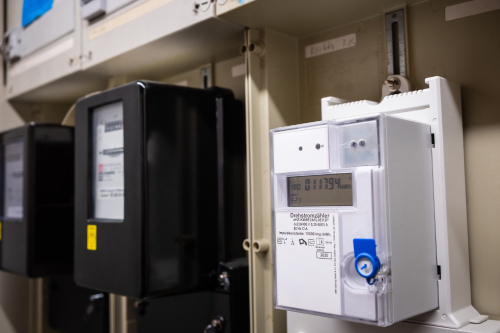 Digitaler Drehstromzähler in einem Schaltschrank neben älteren Stromzählern.