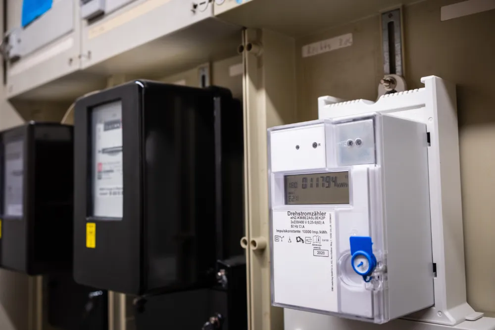 Digitaler Drehstromzähler in einem Schaltschrank neben älteren Stromzählern.