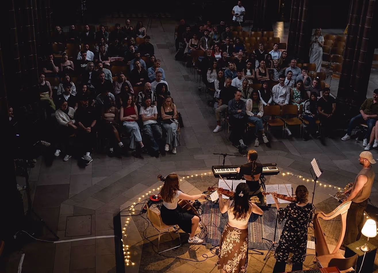 People of various ages and backgrounds gathered in a church, enjoying live music performed by a band.