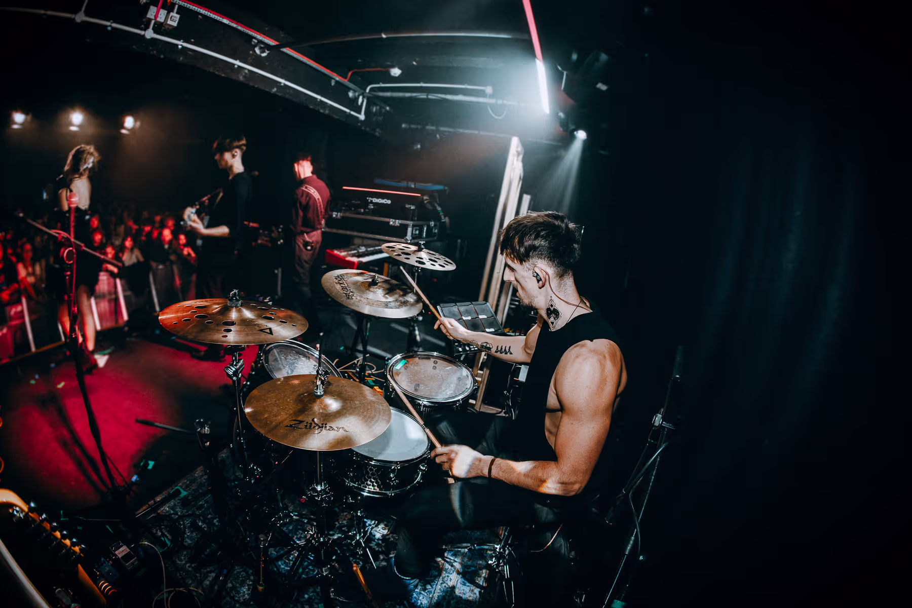 A drummer passionately playing drums on a dimly lit stage.