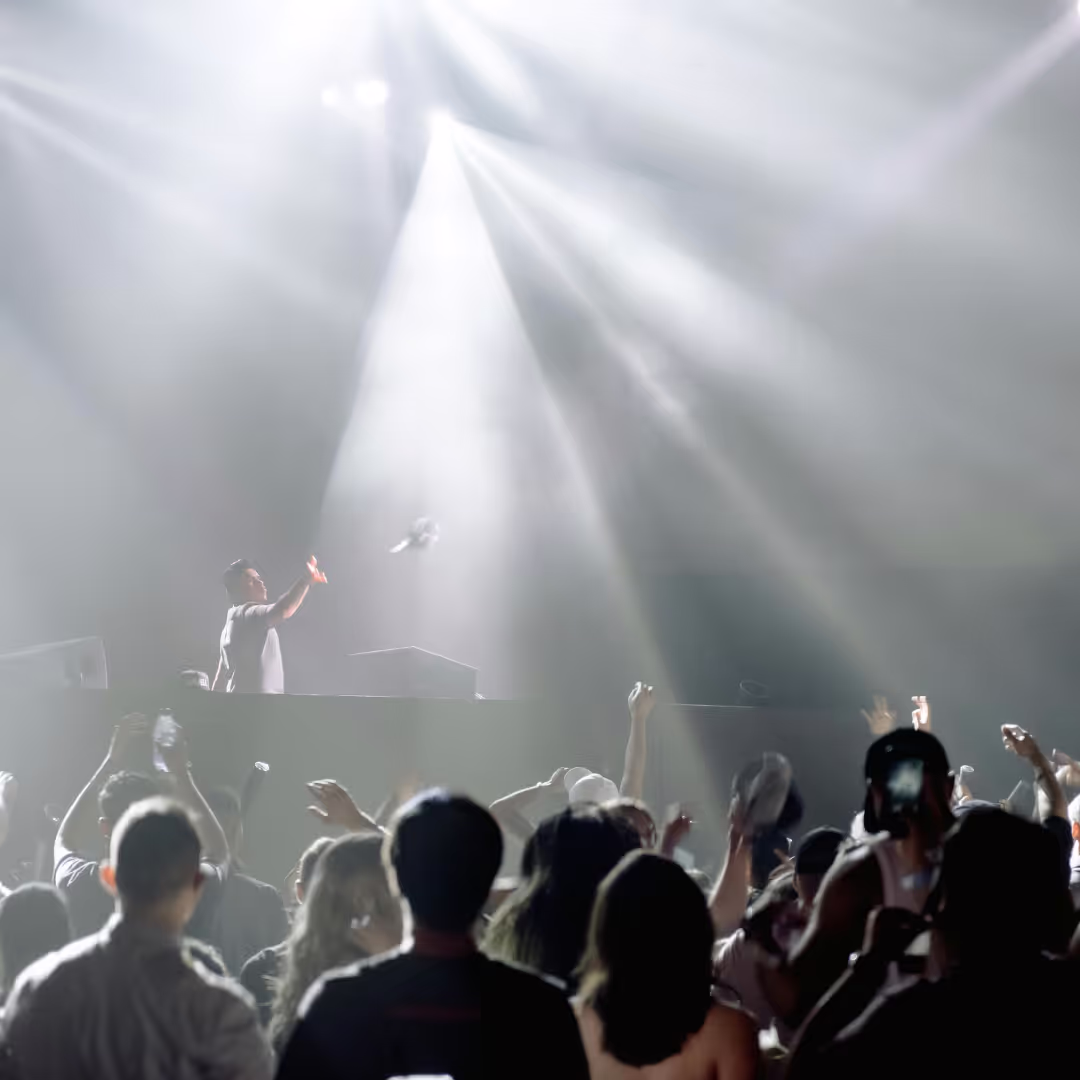 A man sings to a lively crowd and throws his microphone from the stage in excitement