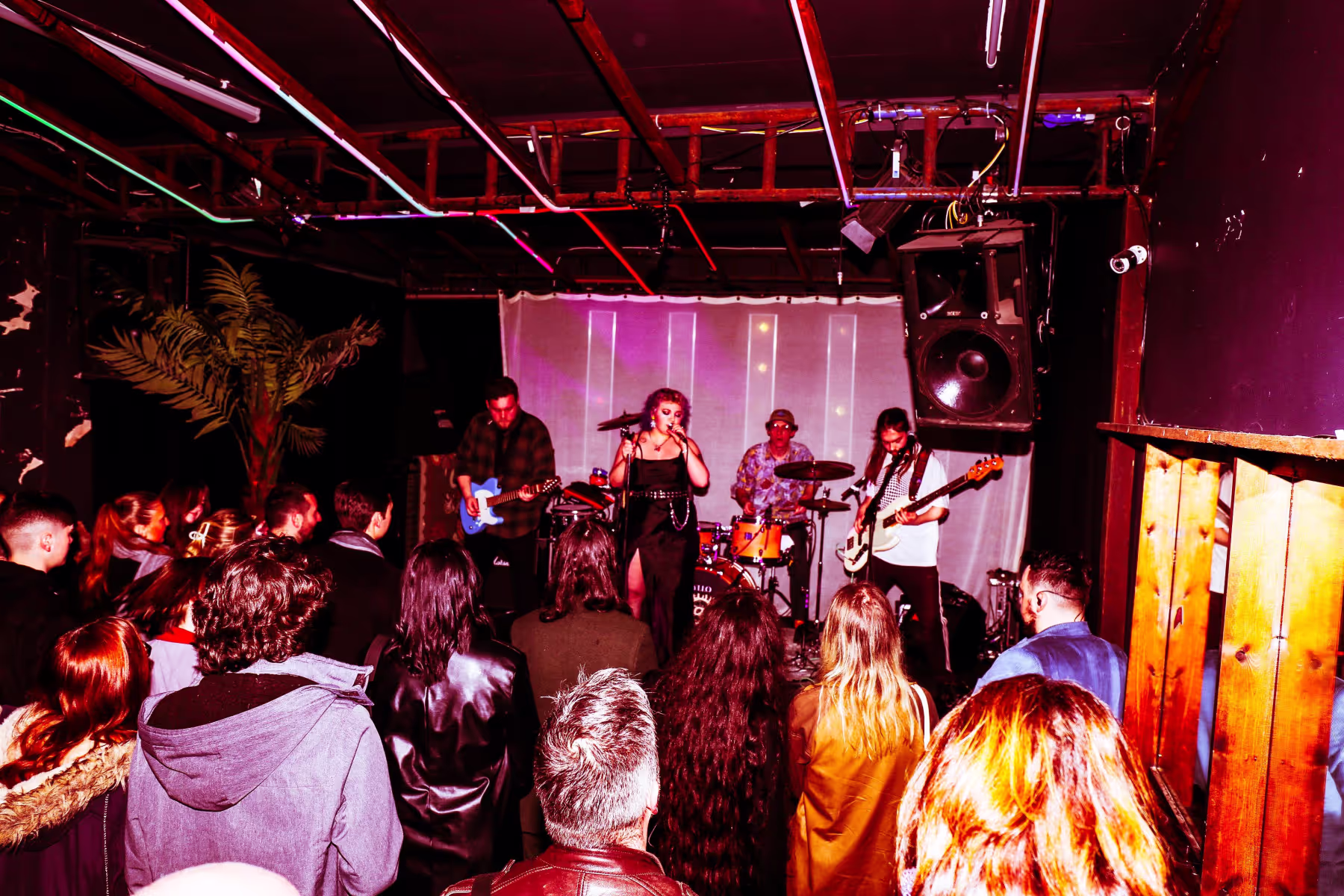 A group of people gathered in a room, watching a band play music on stage.