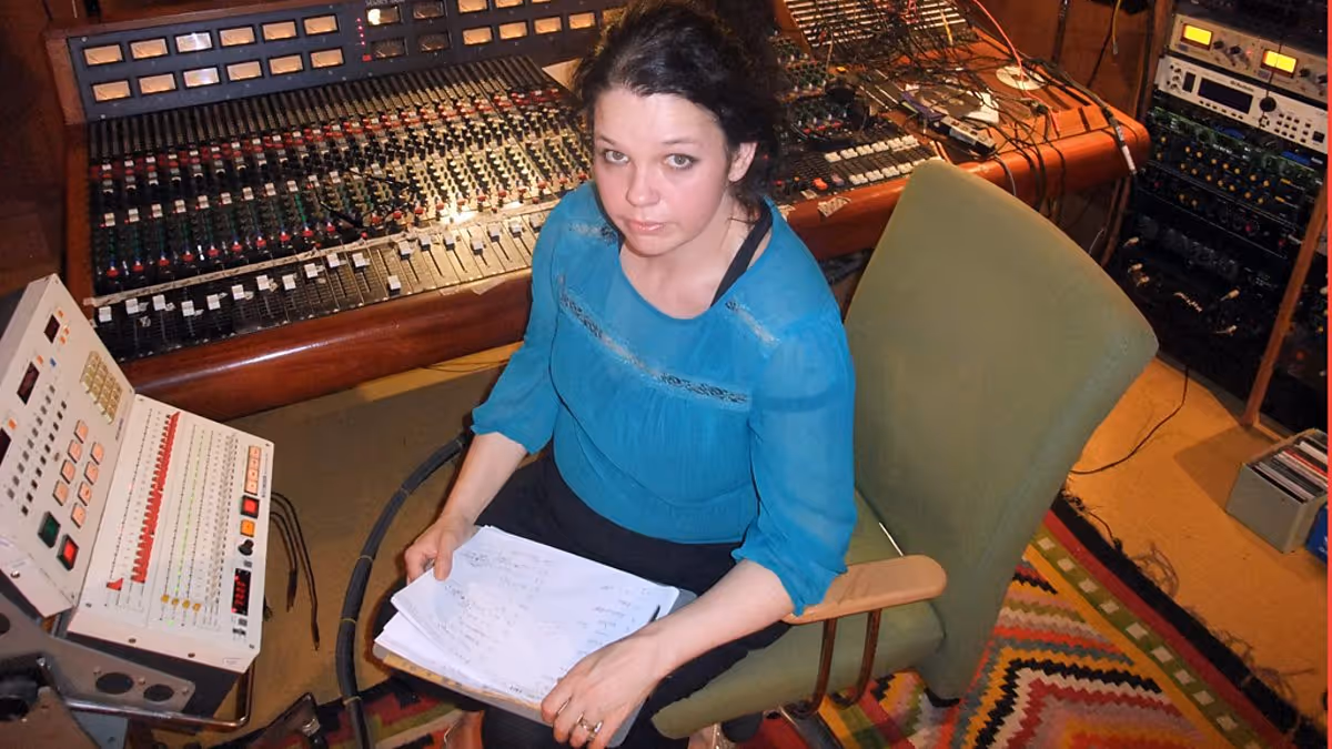 Image of a woman in black smiling at the camera in a music studio 