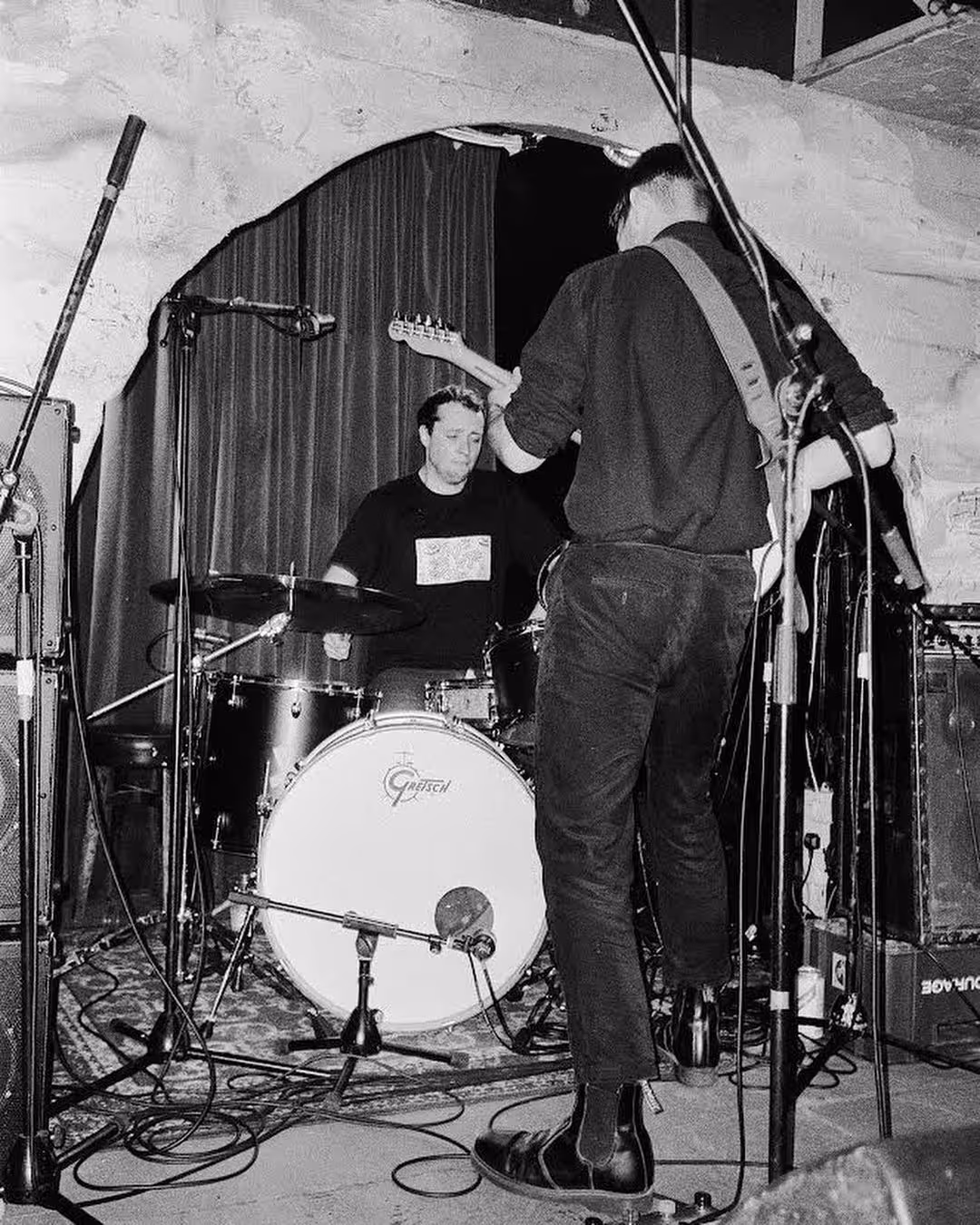 A black and white image of a guitarist and drummer playing music together