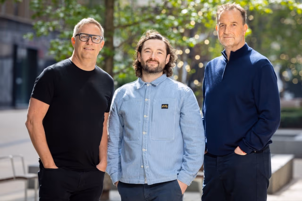Three men stand side by side in front of a building, showcasing camaraderie and a shared moment outdoors.