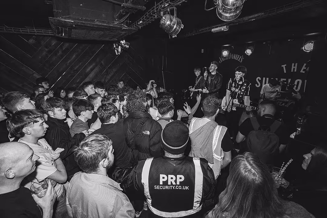 A black and white shot of a large crowd enjoying live music from a band