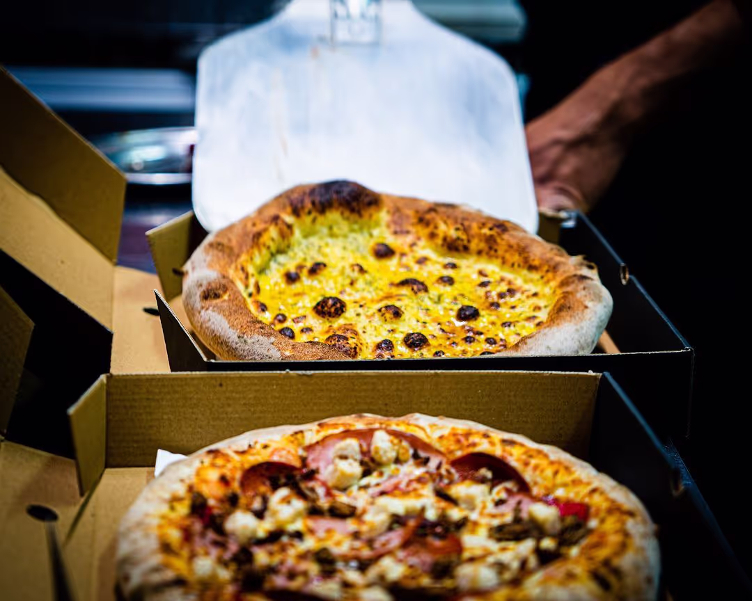 Two delicious pizzas neatly placed in an open pizza box, showcasing their toppings and golden crusts