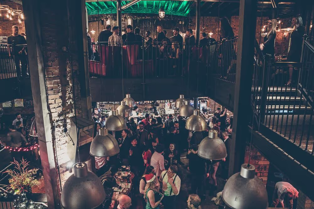 A woman is pulling a pint behind the bar, highlighting the lively setting and social environment of the establishment