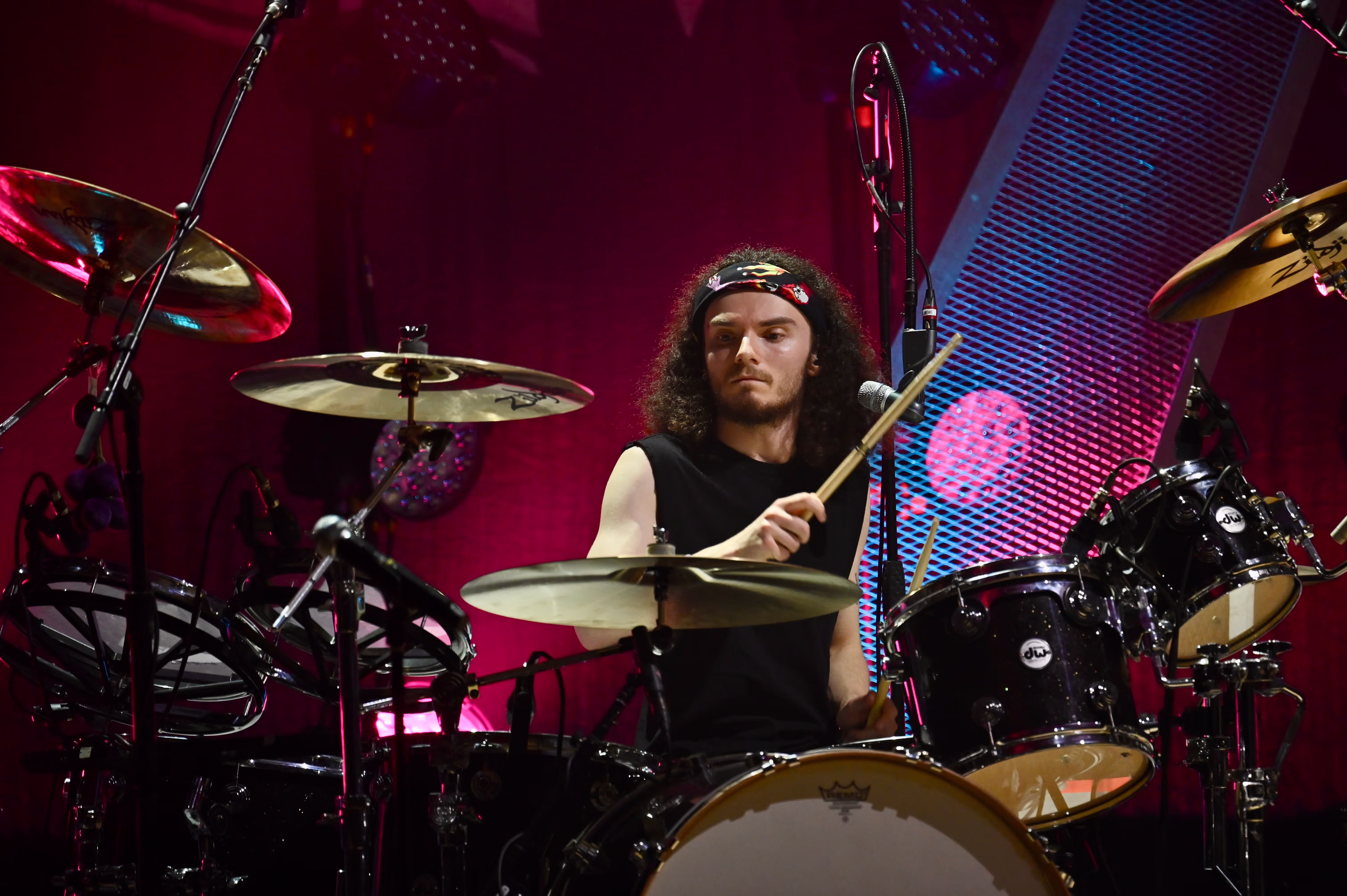 A man wearing a bandana plays a large drumkit