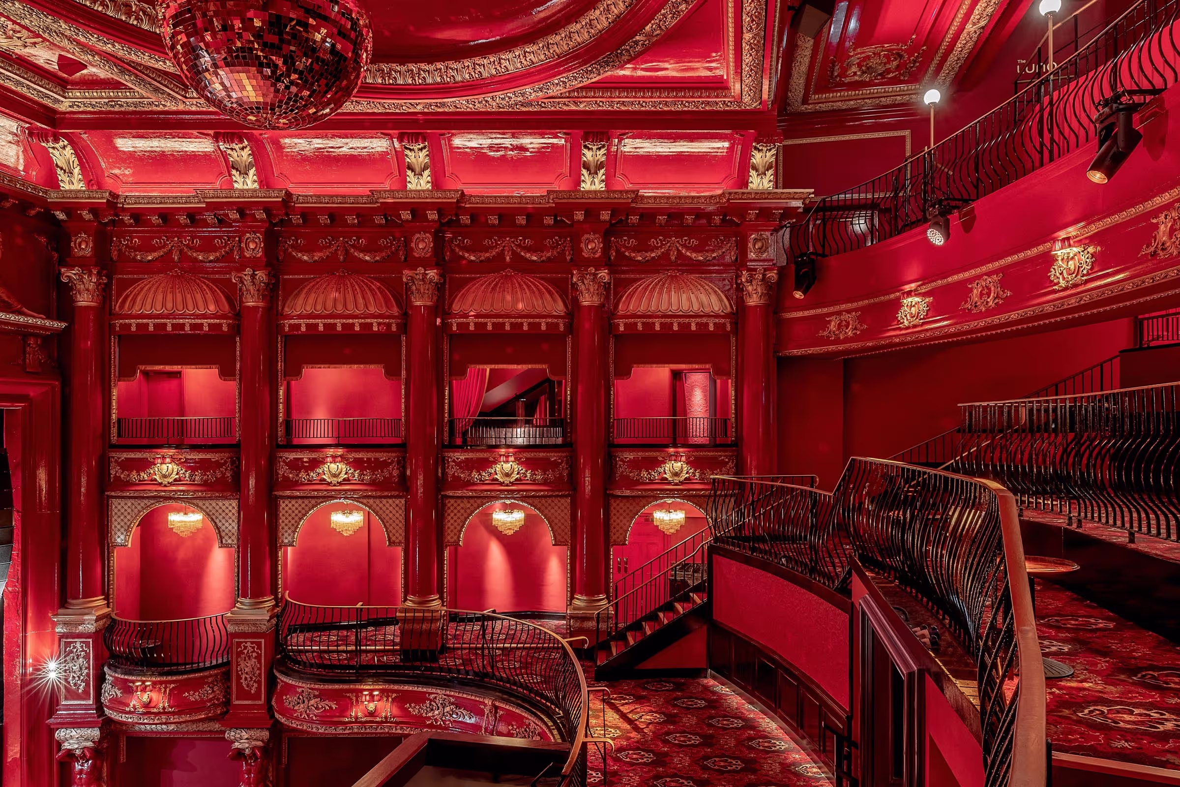 A grand theatre with red interiors and a disco ball on the ceiling