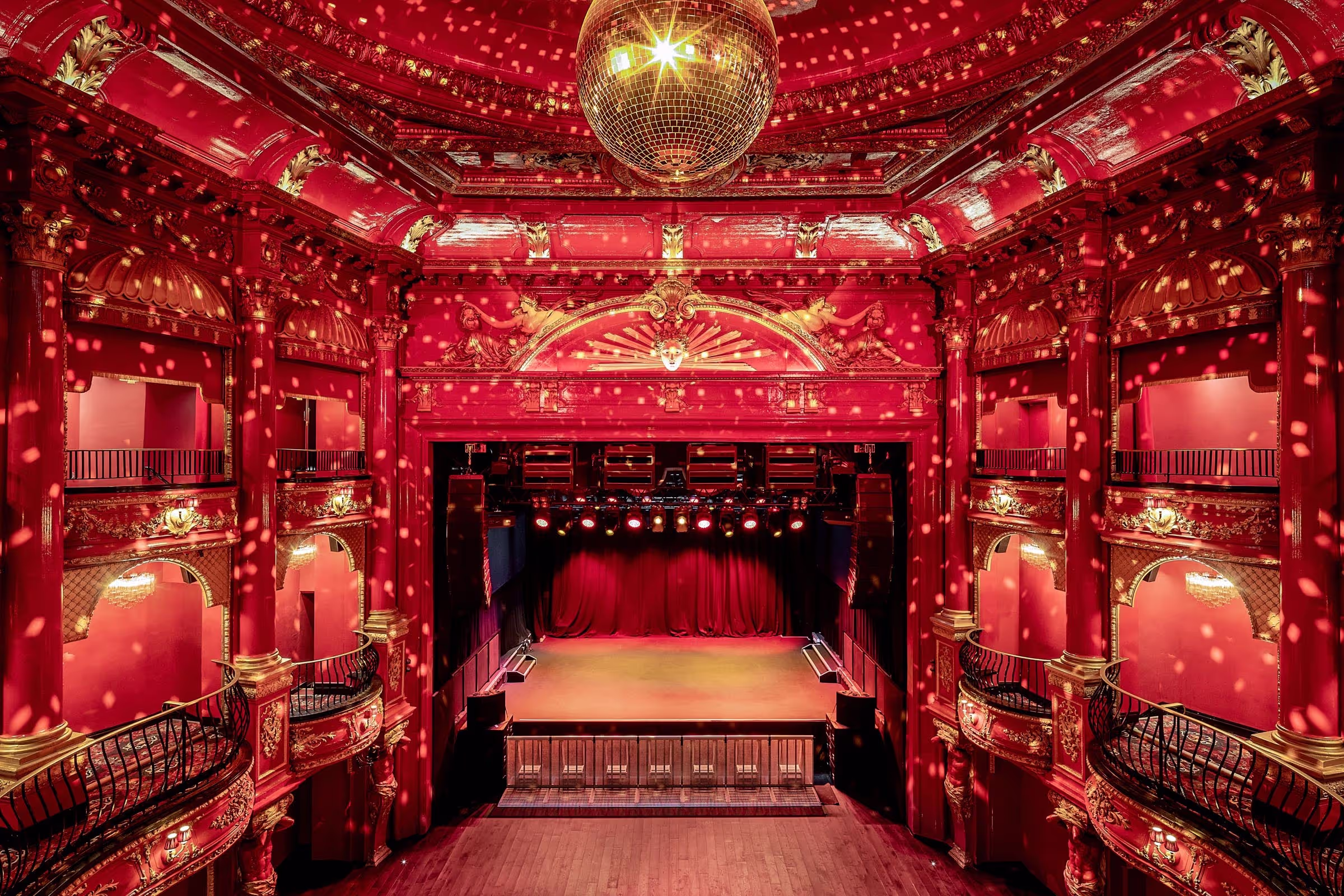 A grand theatre with red interiors and a disco ball on the ceiling 