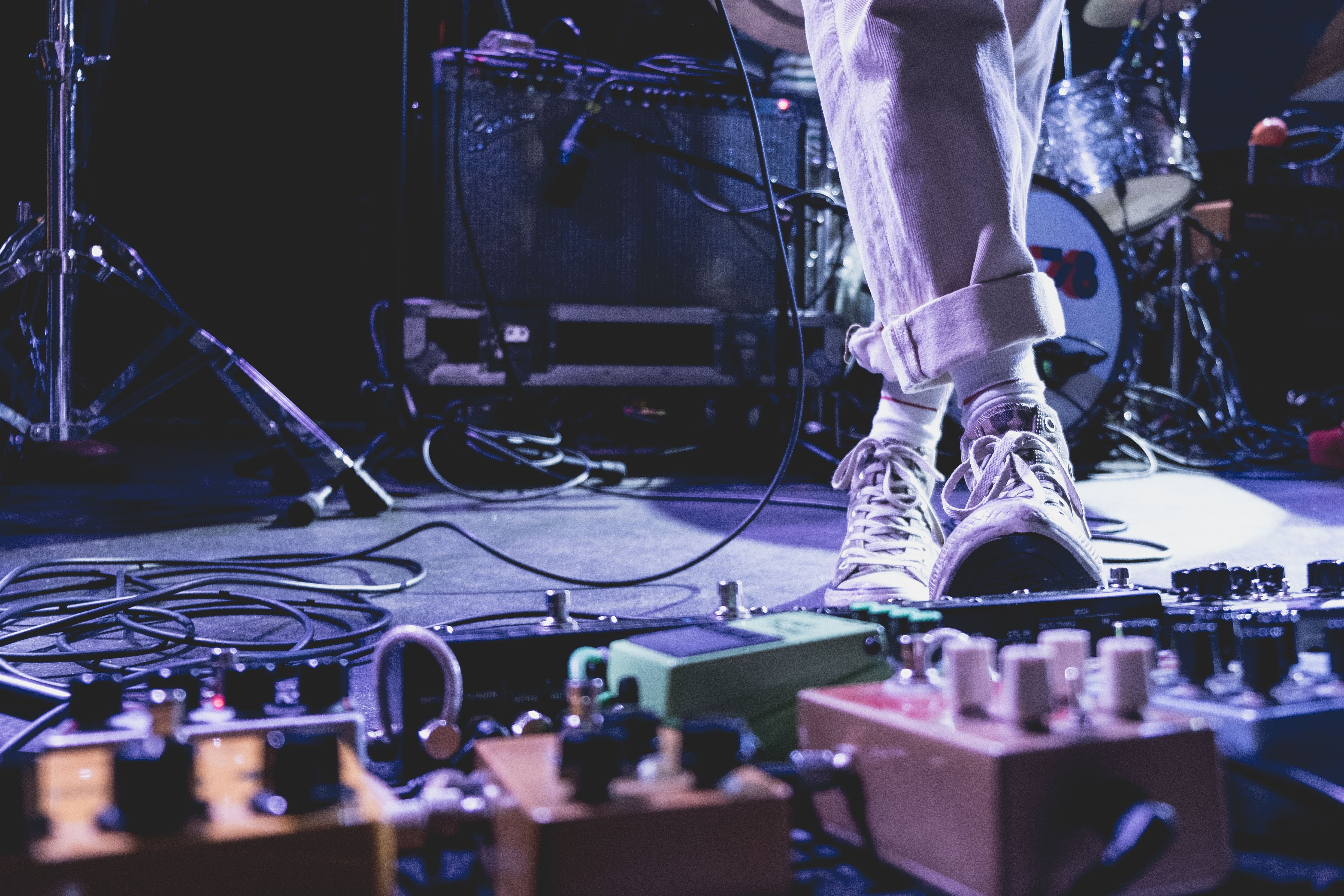 A performer on stage with a guitar and an array of pedals, poised to deliver a musical performance