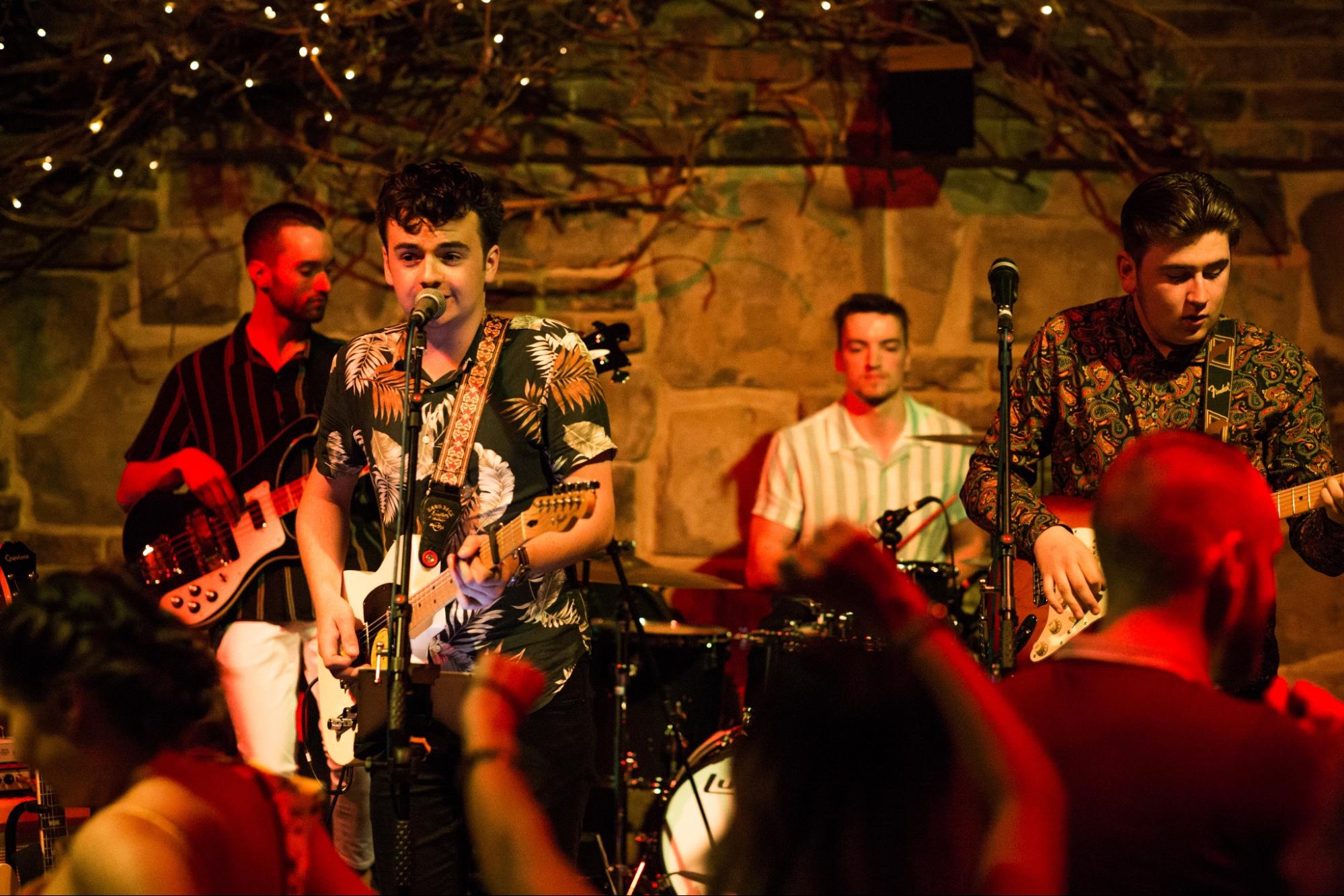 A lively band performs in a bar while an engaged audience watches and enjoys the music