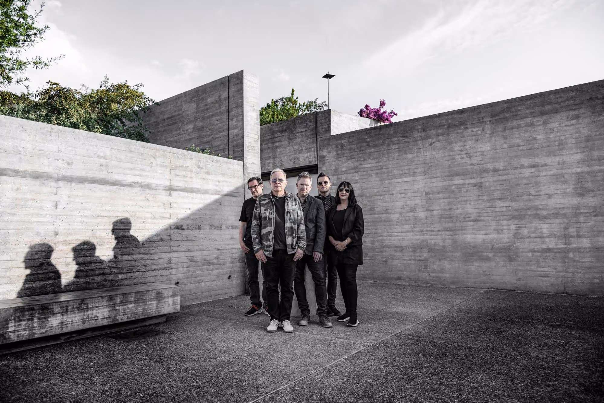 A diverse group of individuals poses together in front of a textured wall, showcasing unity and camaraderie
