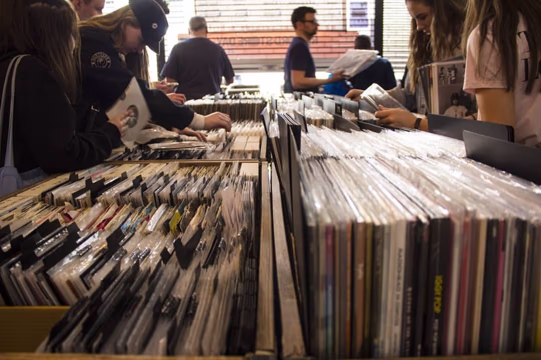 A group of individuals browsing through vinyl records in a vibrant record store, exploring various music genres