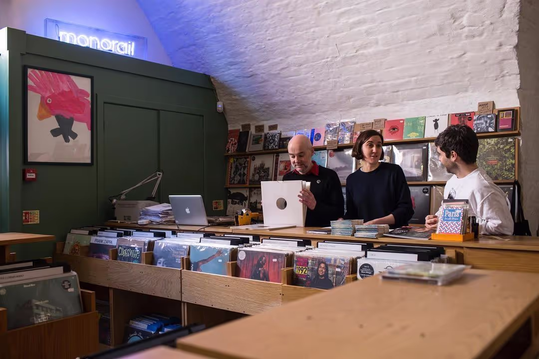 A couple stands in a record store, showcasing their interest in music amidst vibrant album displays