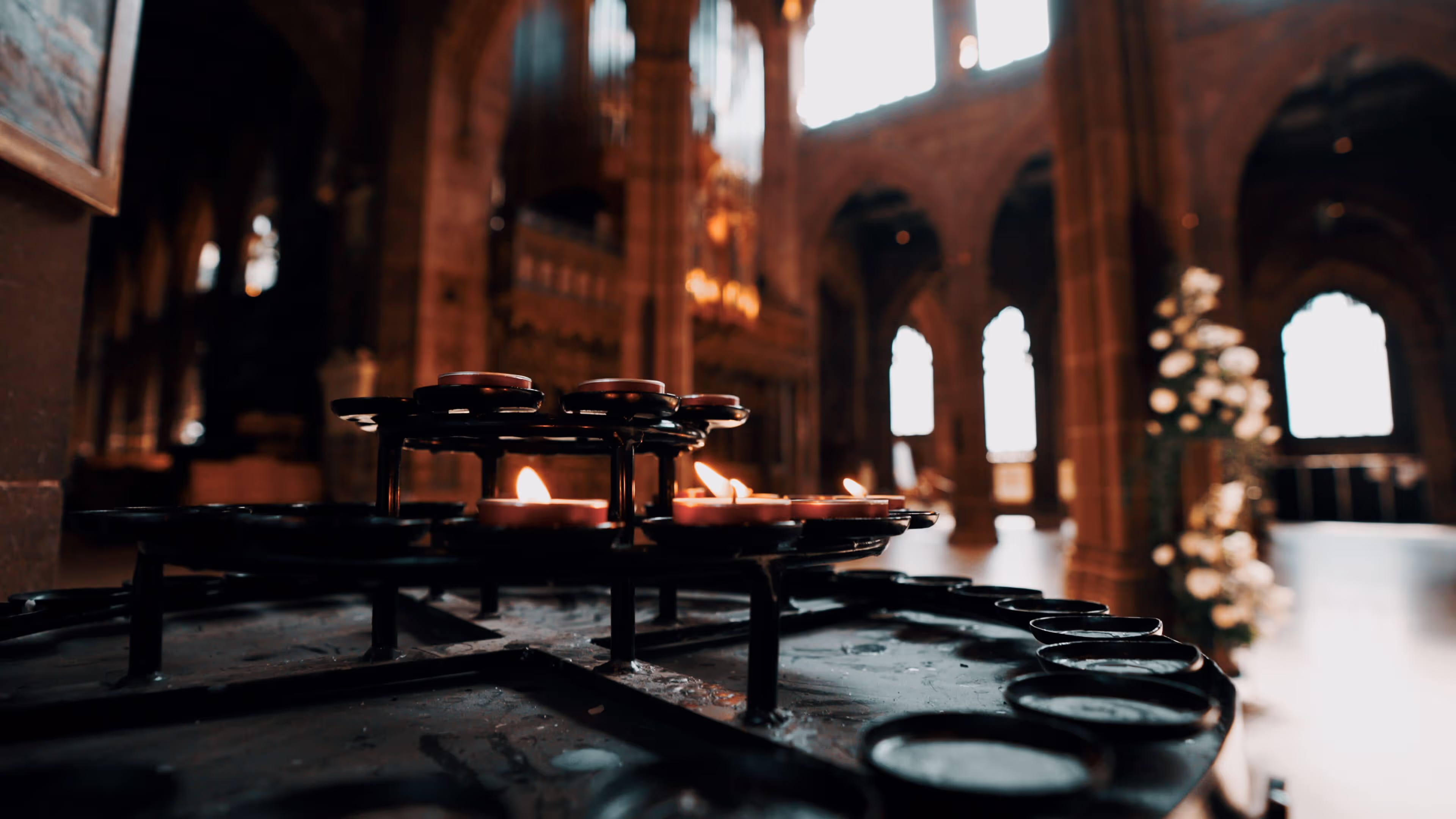 Candles illuminate a church table, with a majestic cathedral visible in the background.