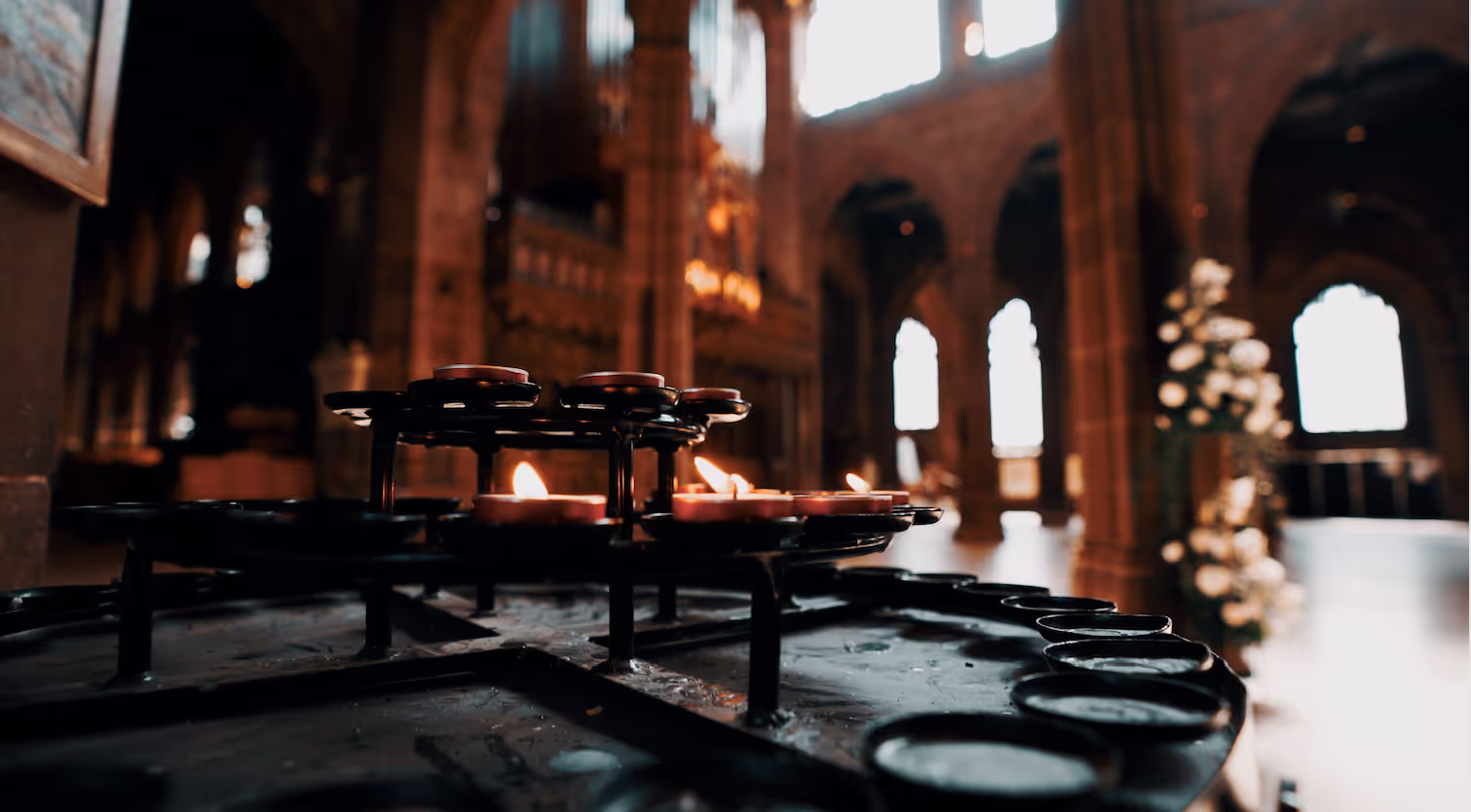 Candles illuminate a church table, with a majestic cathedral visible in the background.