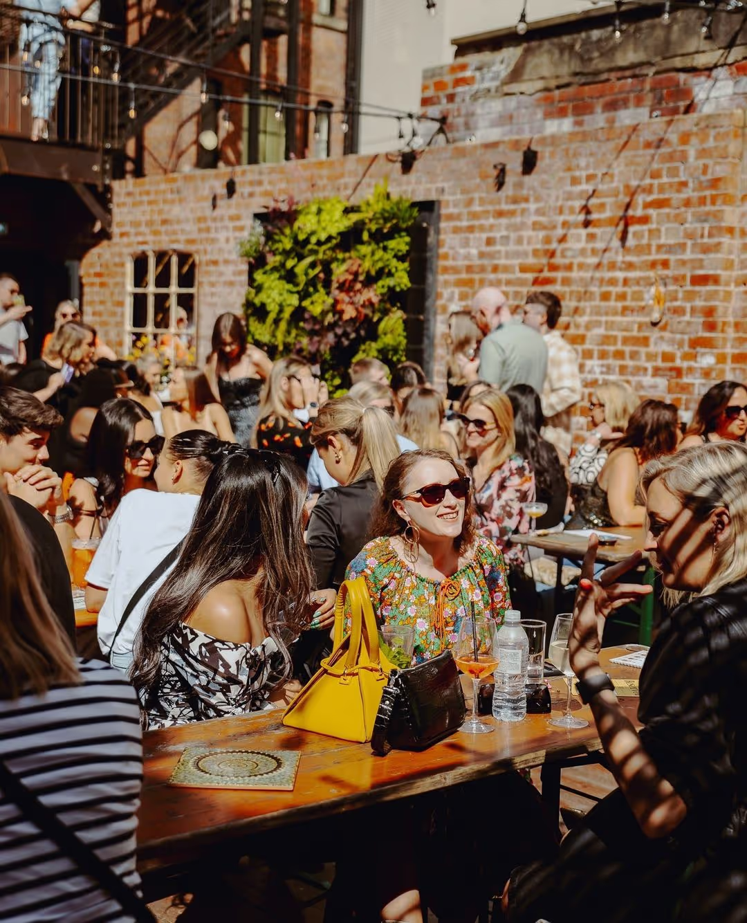 A crowd of smiling people are enjoying the sun in a beer garden