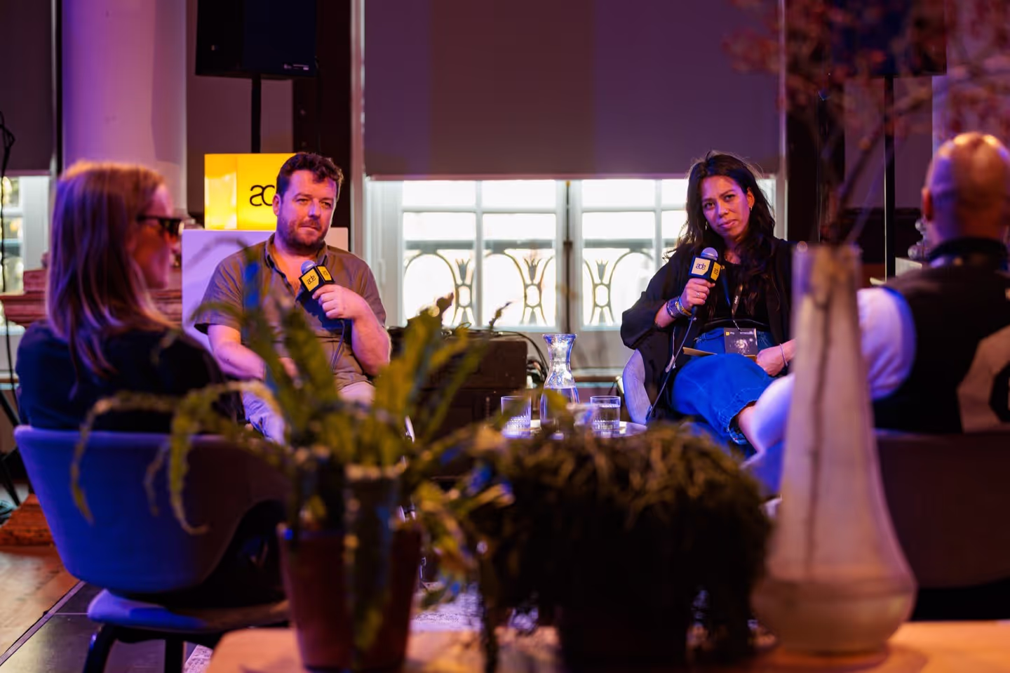Four people sitting together holding microphones and looking deep in thought in an interview