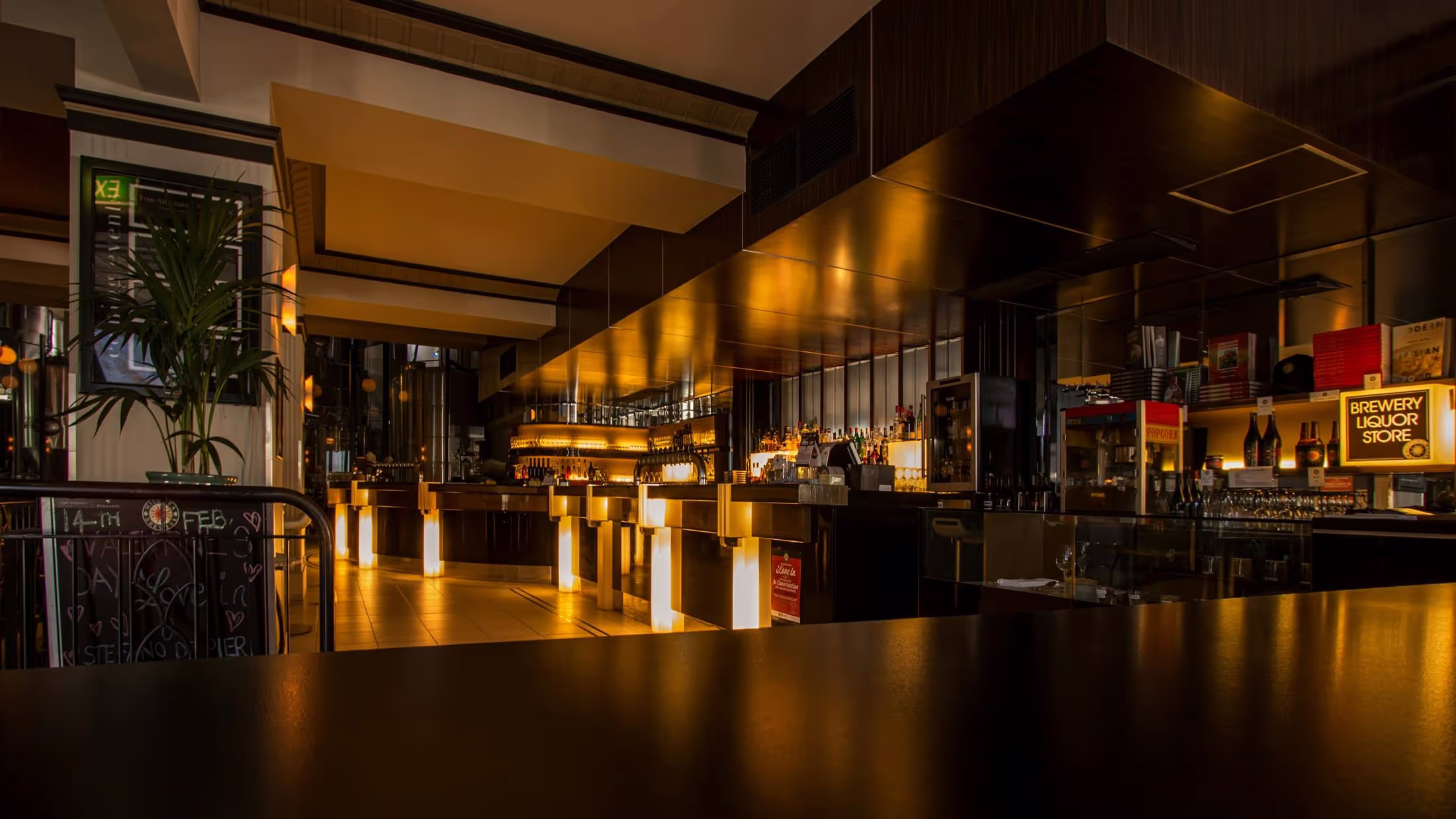 A large, stylish, dimly lit bar stands empty
