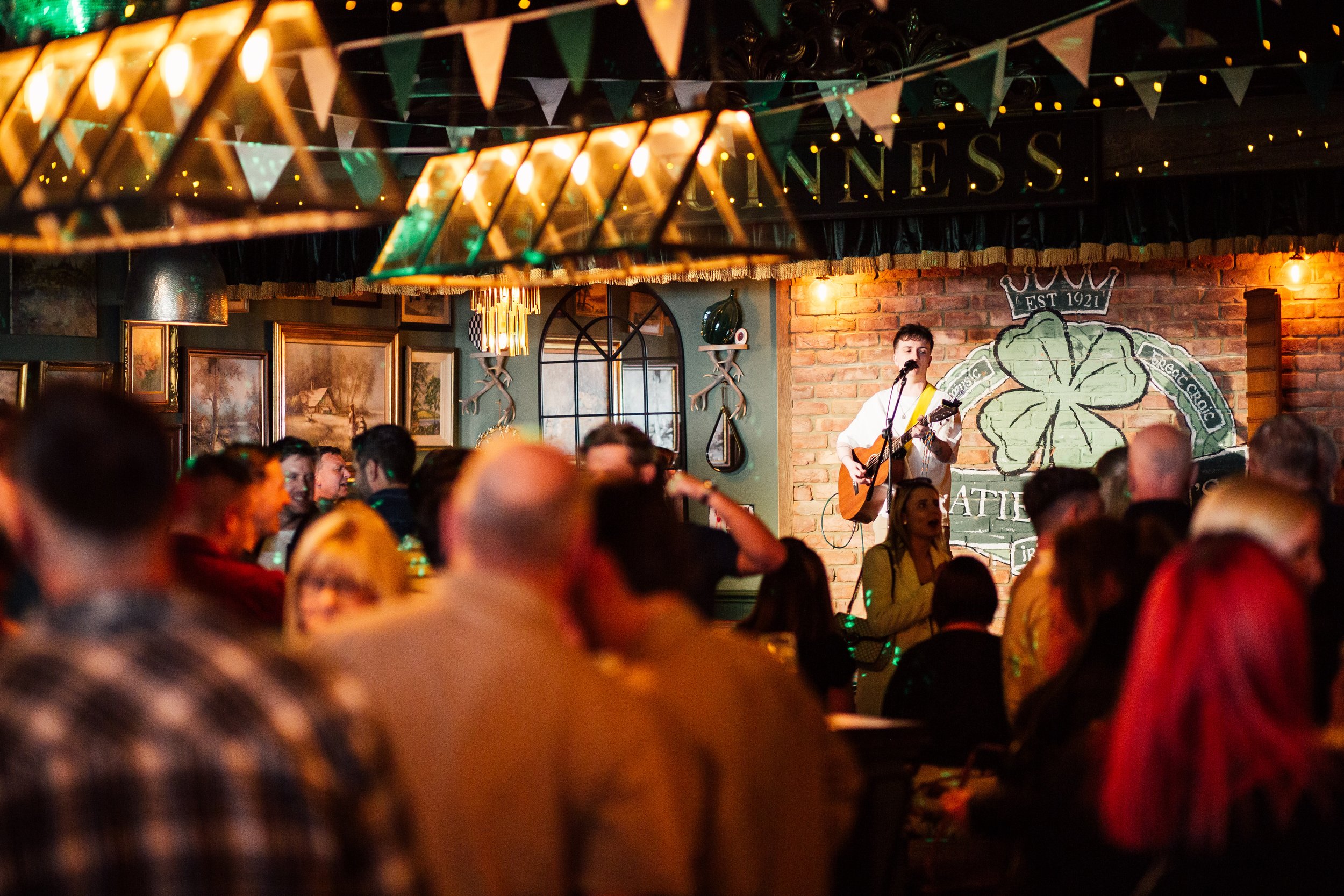 Man playing the acoustic guitar and singing on a stage in an Irish pub
