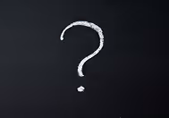 Signo de interrogación de tiza blanca dibujado en una pizarra negra.