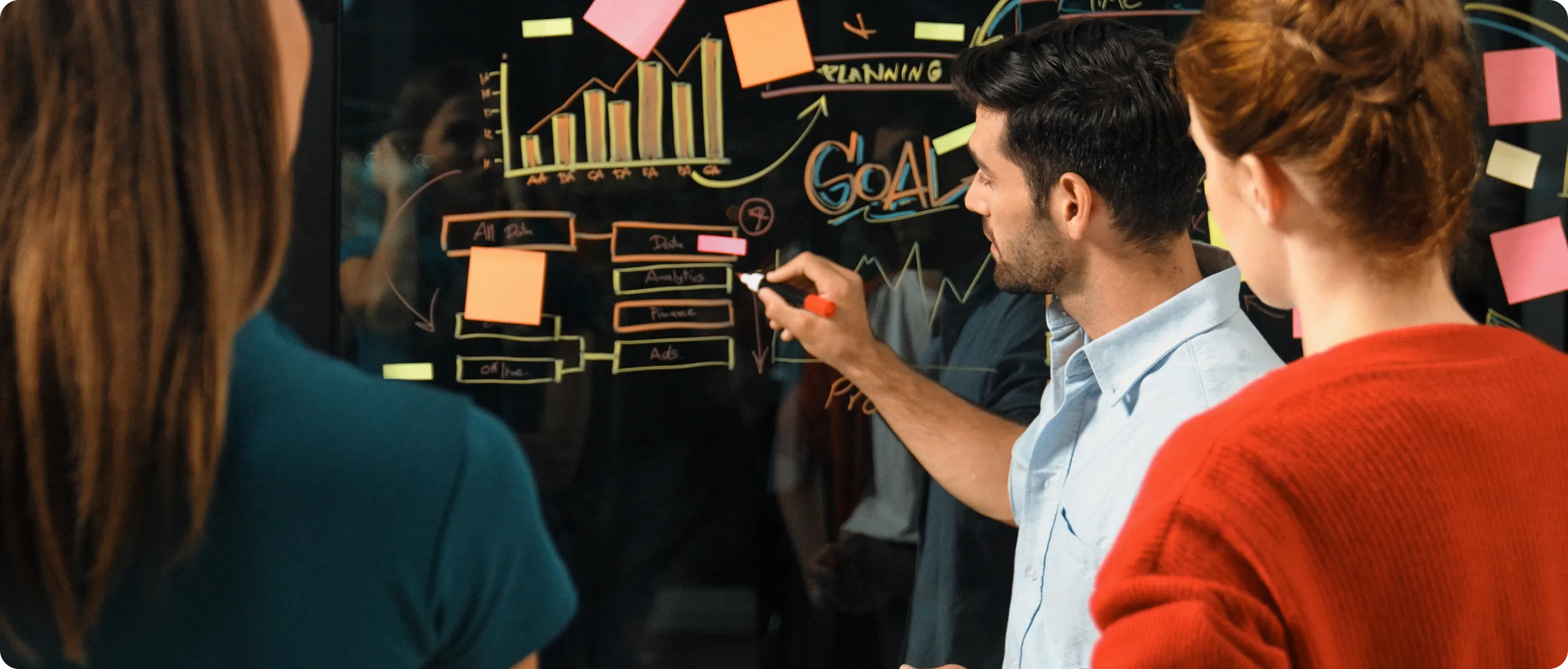 Homem sorridente de moletom laranja sentado em poltrona, usando smartphone. Ao fundo, telas flutuantes exibem gráficos de desempenho e sessões agendadas, em estilo moderno e digital.