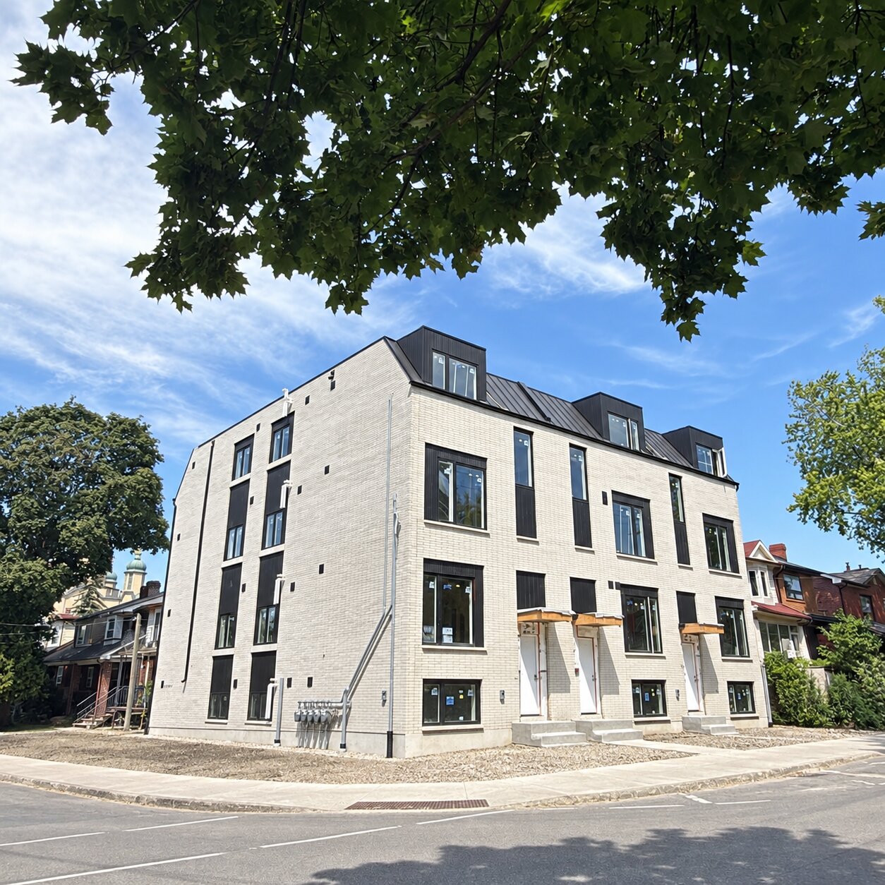 Corner view of Christie Pits' light brick building with three front entrances and dormer windows.