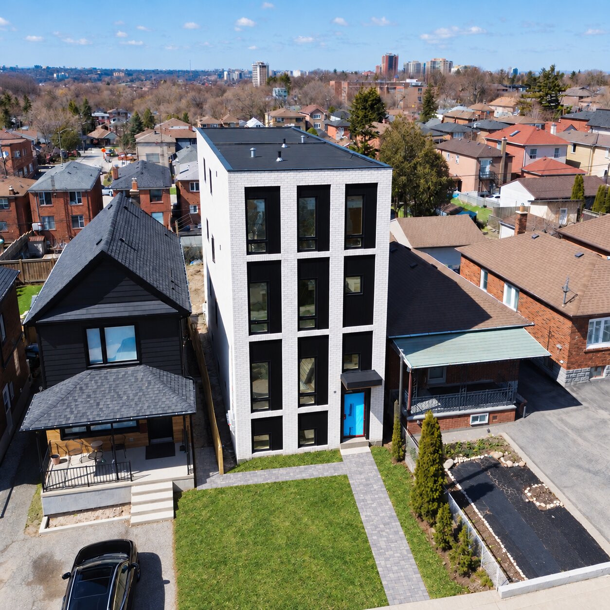 Elevated view of Fairbank 2's light brick facade, black window trim, and front lawn among neighbouring homes.