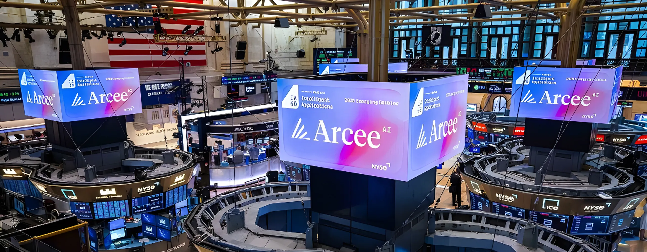 New York Stock Exchange trading floor with multiple large digital displays showing Arcee AI branding and logo with blue and purple gradient backgrounds
