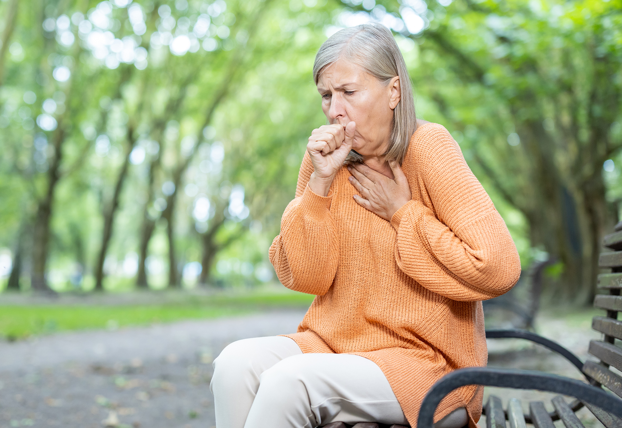 Woman holding chest coughing