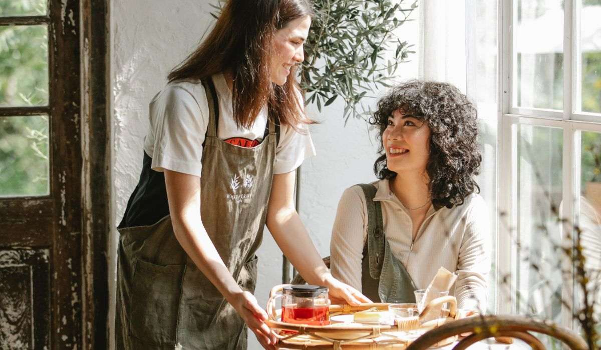 Garçonete conversa com cliente em restaurante.