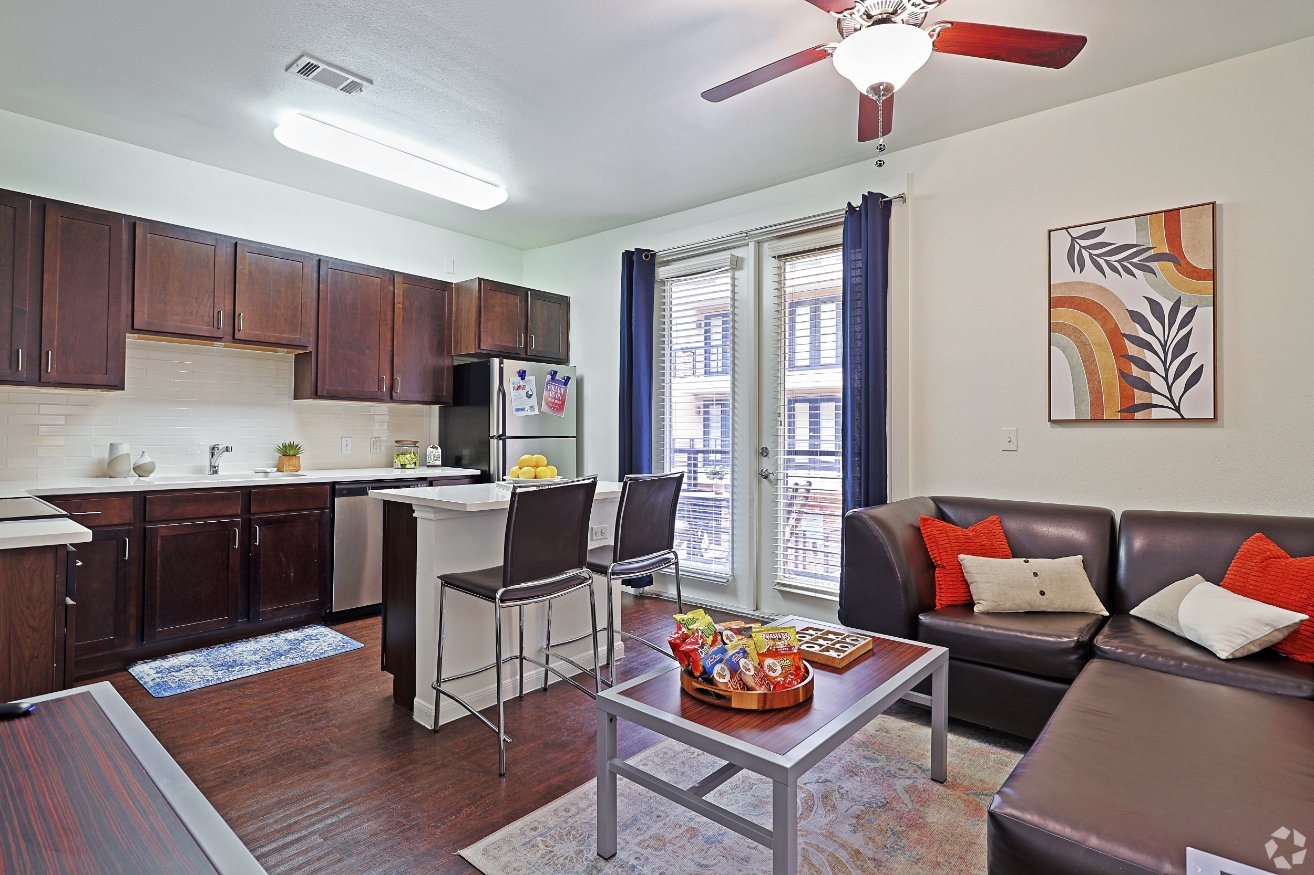 Living area with sofa, modern wall art, and coffee table with snacks and view into kitchen with island