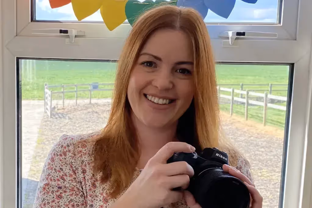 Woman smiling holding an SLR camera