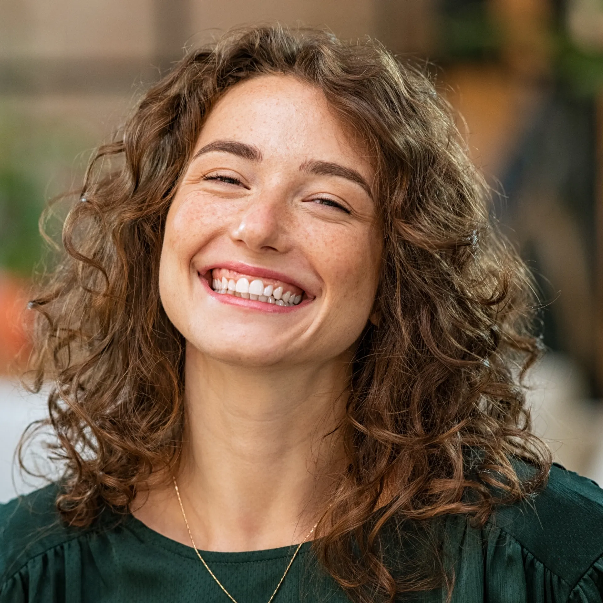 A woman with curly hair smiling at the camera.